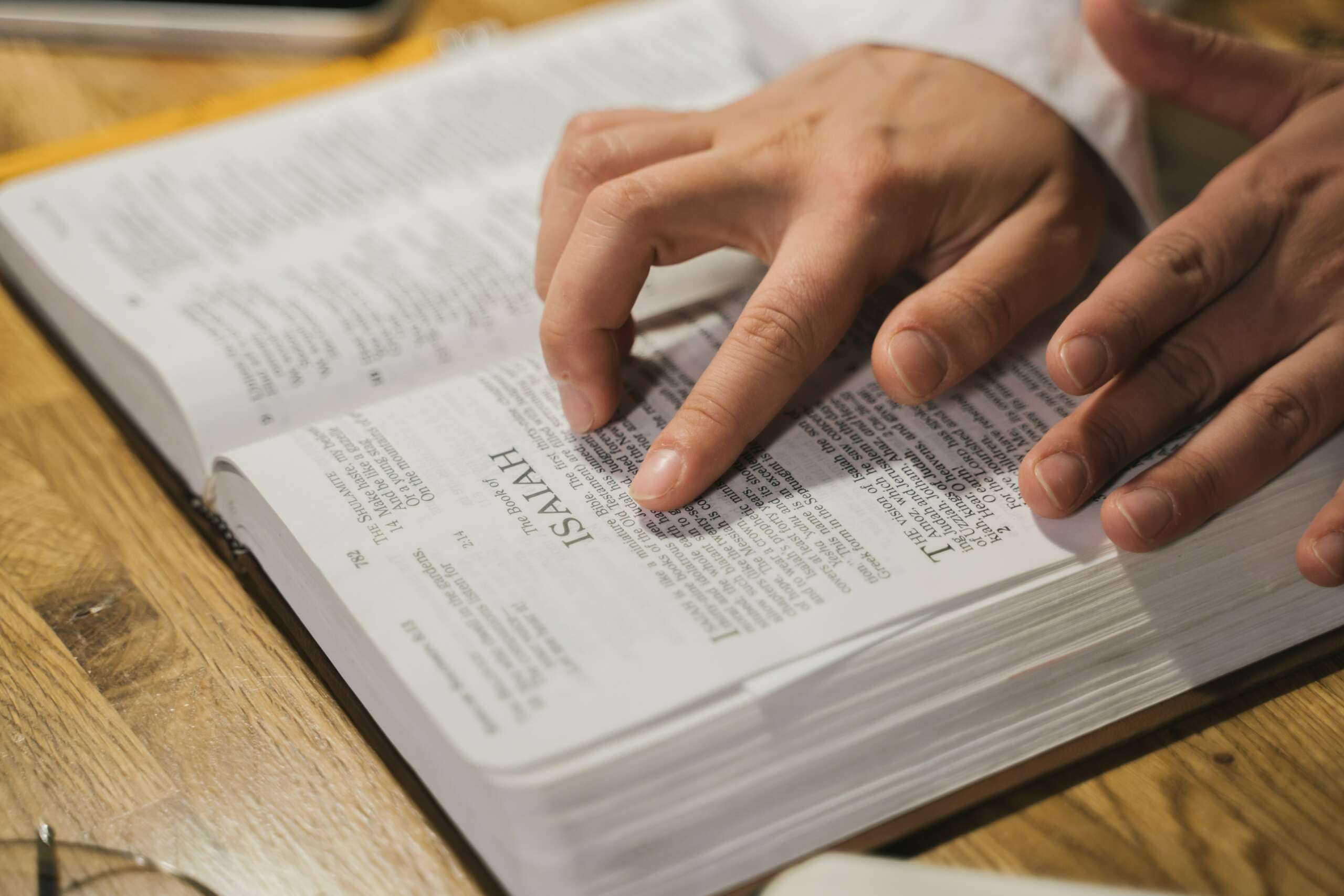 A man's hand pointing to a verse in the Bible.