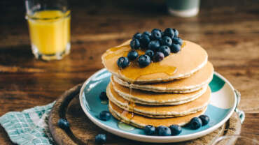 Blueberry pancakes on a plate with orange juice.